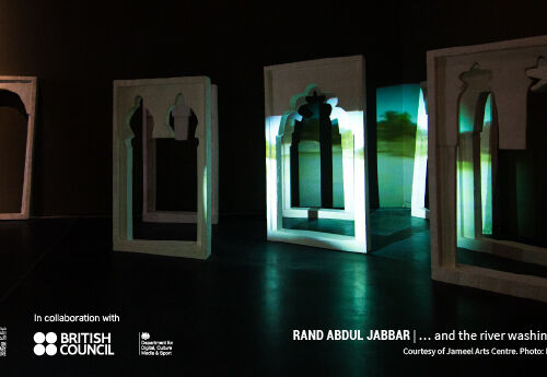 A picture of an exhibition by Rand Abdul Jabbar. A darkly lit room displays freestanding windows from the Minaret of 'Anah