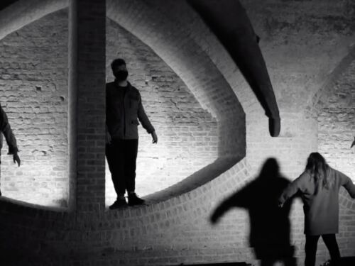 Figures silhouetted against dramatic brickwork.
