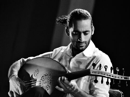 Spotlit performer playing an oud
