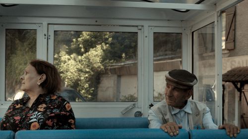 An elderly man and woman sitting on a bus