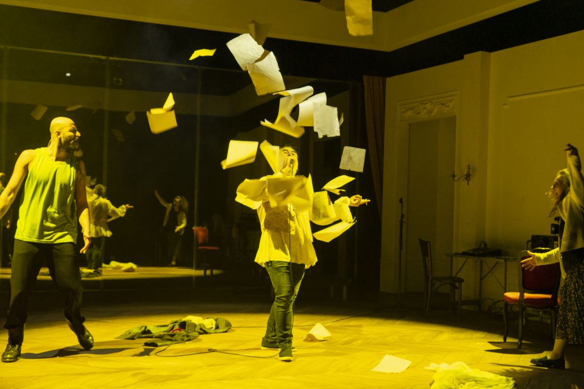 A image of a woman in a studio throwning an armful of paper into the air