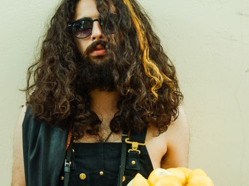 Beardy long-haired man in dungarees holds plate of lemons