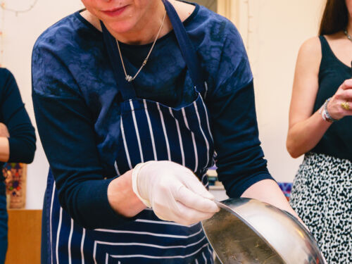 A cook lifting the lid on a rice and aubergine dish