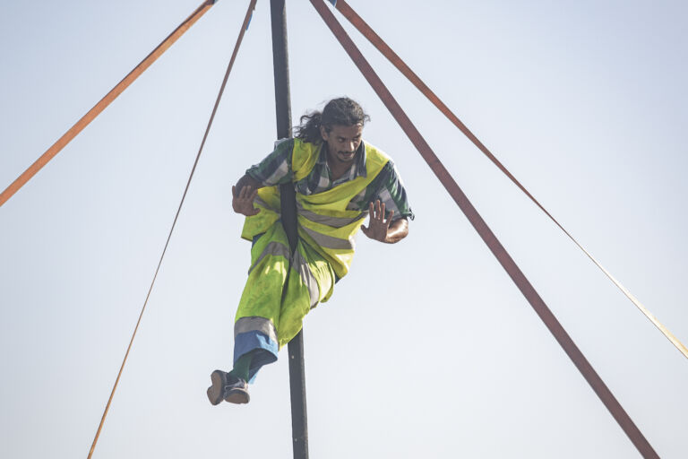 Man doing acrobatics on a pole wearing hi-vis clothes