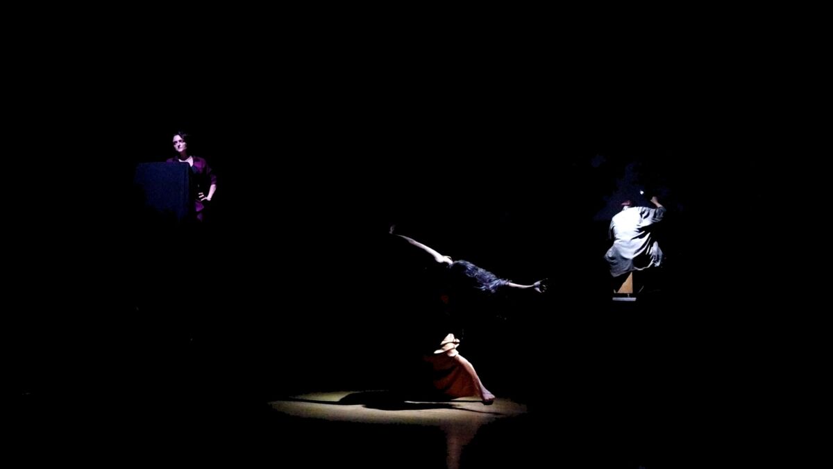 Image of performer moving, dancing in darkness