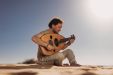 man playing oud in a desert